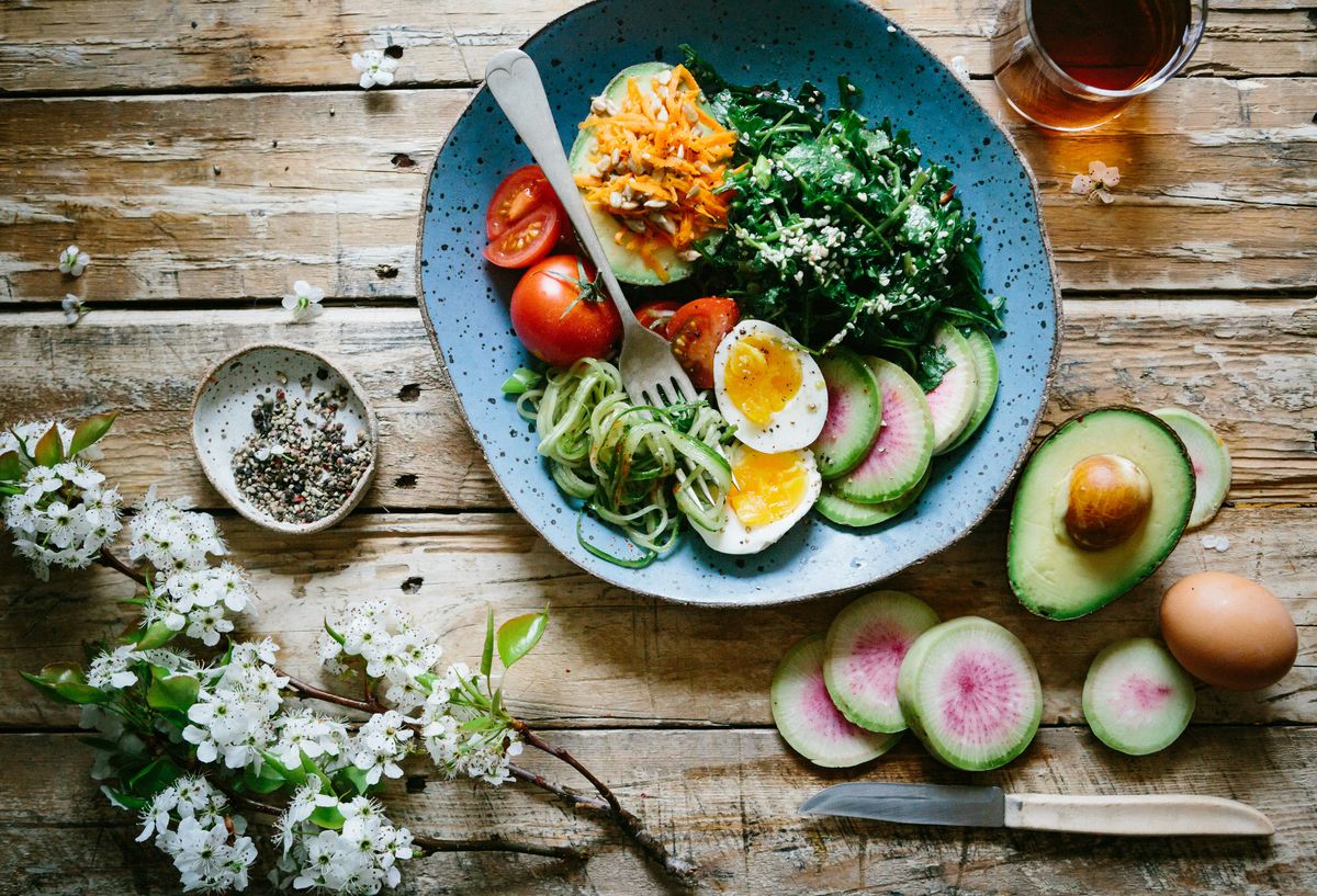 Posjert egg med tomater og grønnsaker servert på blå tallerken