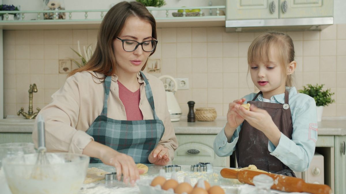 Kvinne og barn baker sammen med mel og utstikkere på kjøkkenet