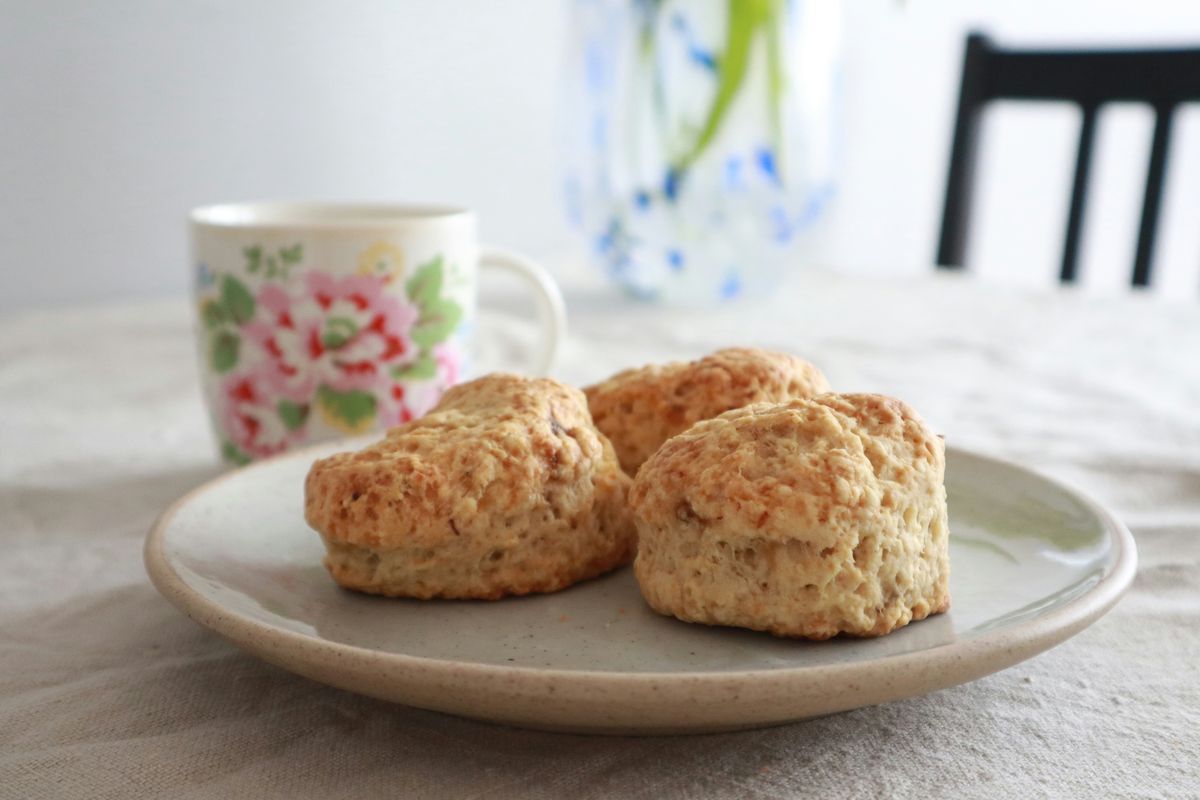 Tre lyse scones på en tallerken ved siden av en blomstret kopp